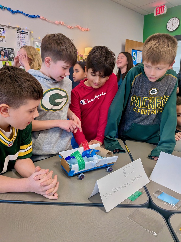 Boys standing in classroom and smiling a project they created.