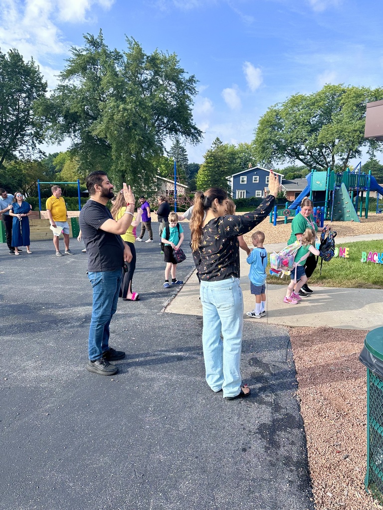 Two kindergarten parents smiling and waving as their son entered the school on the first day.
