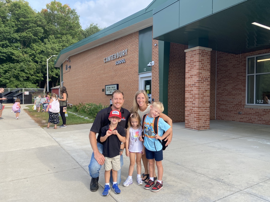 Family with three students posing in front of the school
