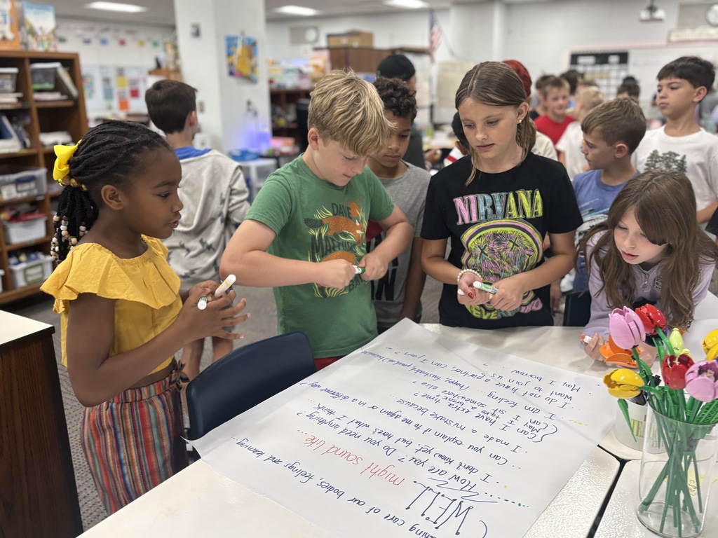 Students working together posting ideas with post its on a white paper.