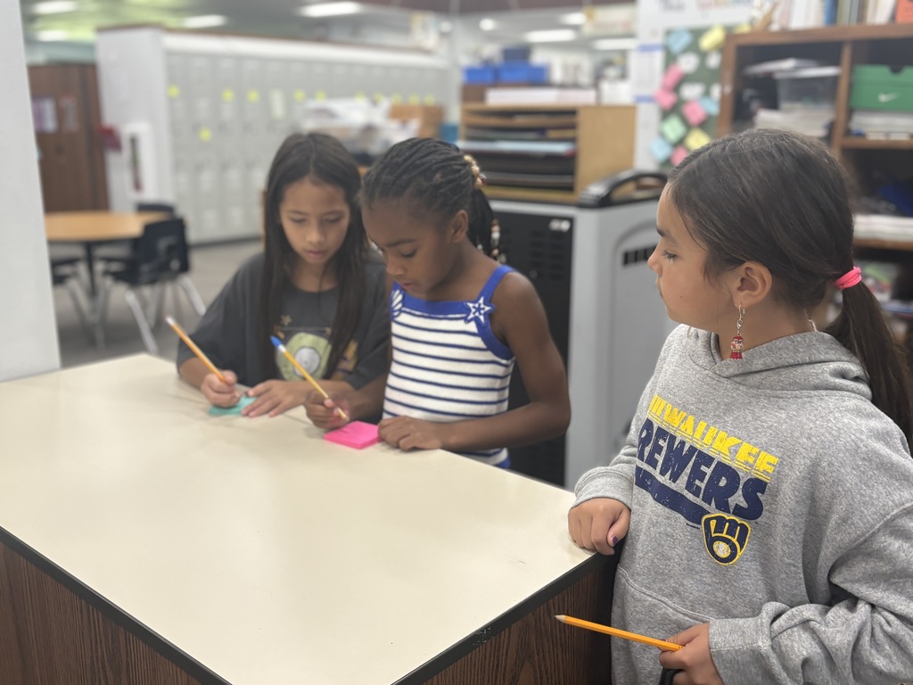 Three students working on post its of class traits.