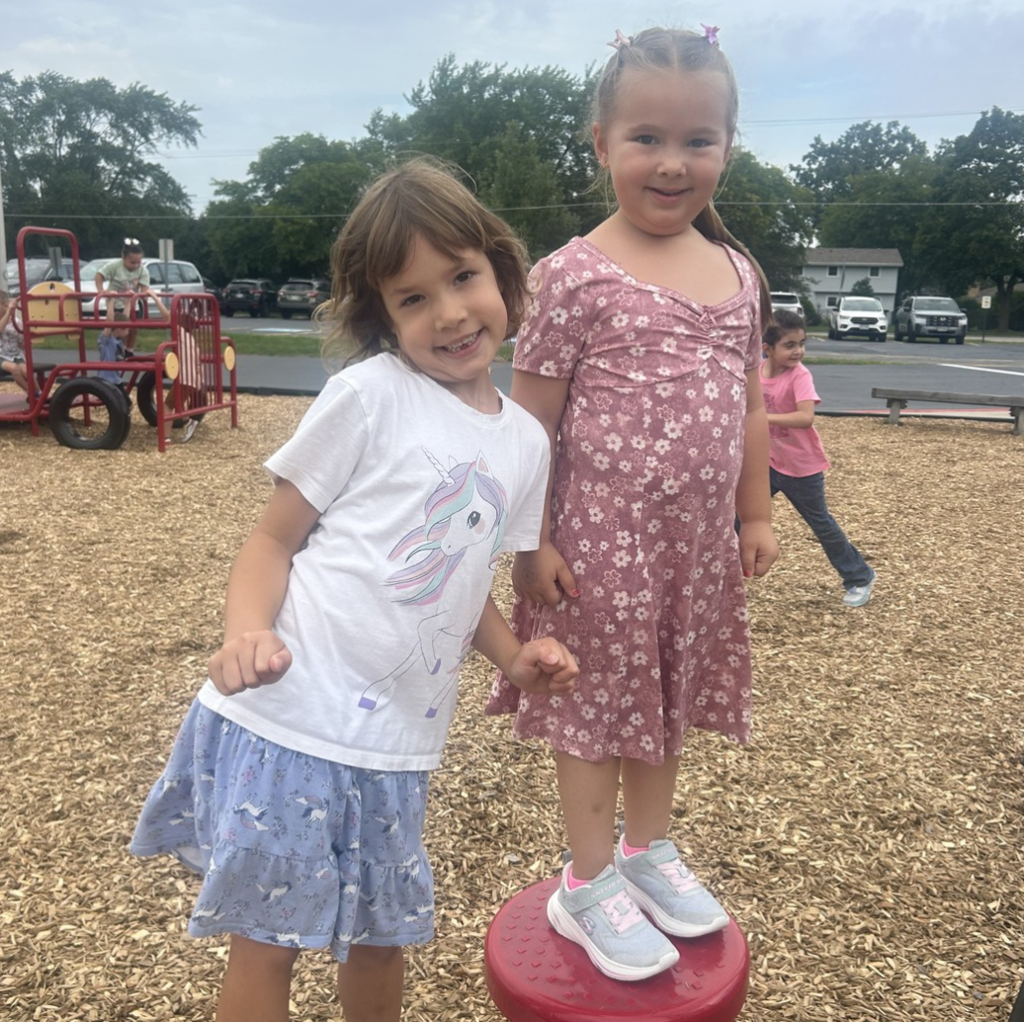 Two 5K girls smiling together out on the playground.