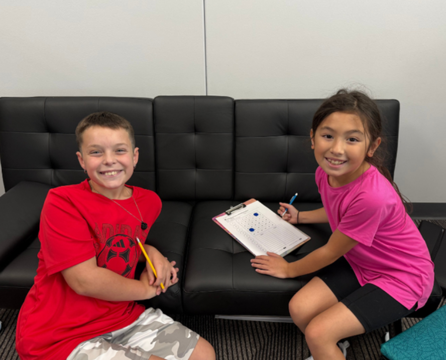 Two fifth grade classmates smile while working on a classroom scavenger hunt.