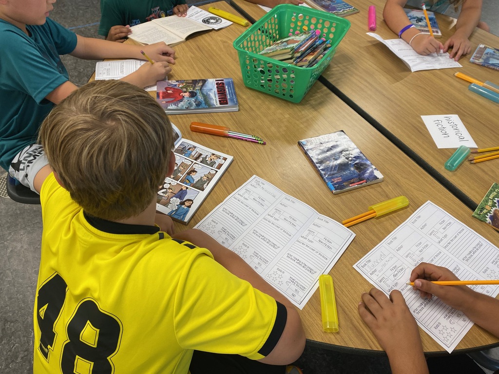 Students smiling while looking at books and completing worksheets