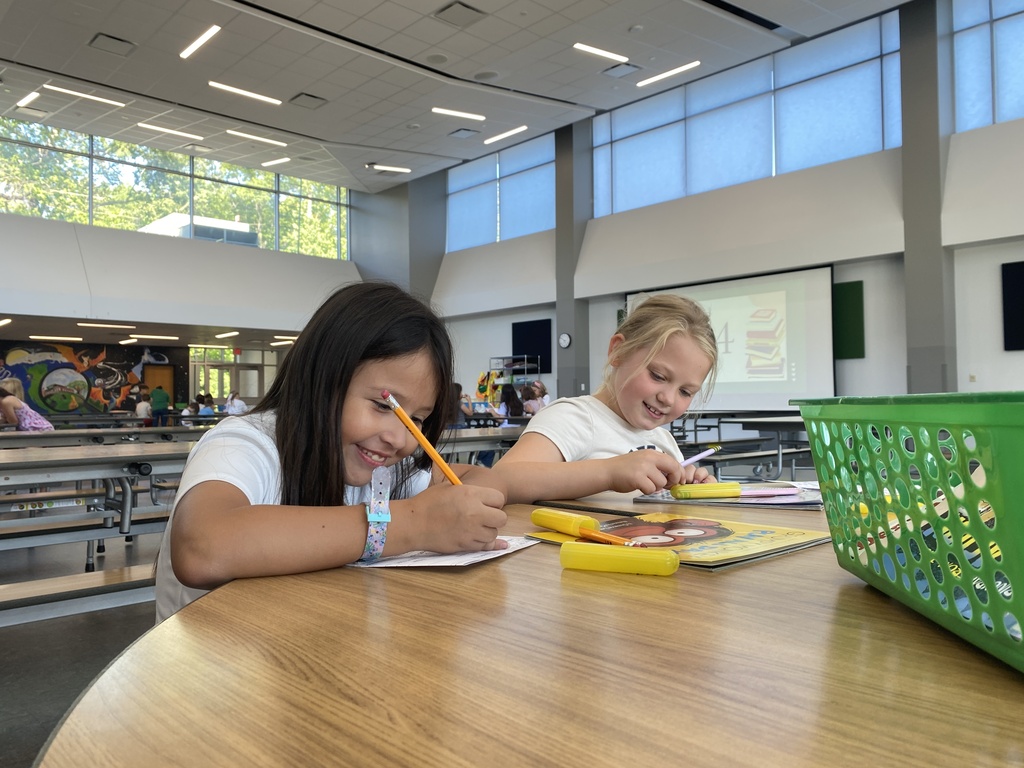 Students smiling while looking at books and completing worksheets