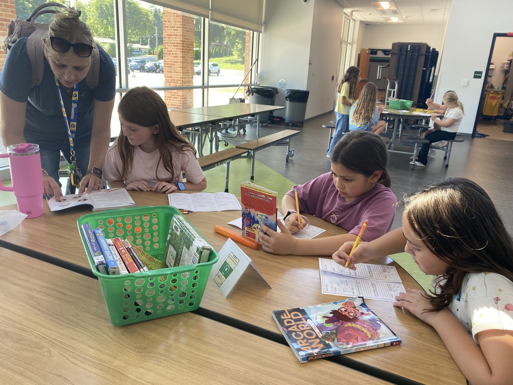 Students and a staff member looking at books and completing worksheets