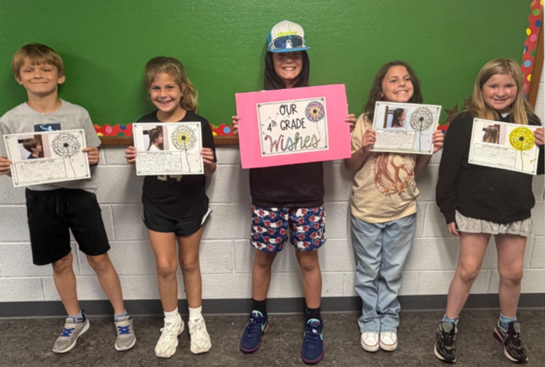 Five students posing and holding a paper that shows their 4th grade wishes.
