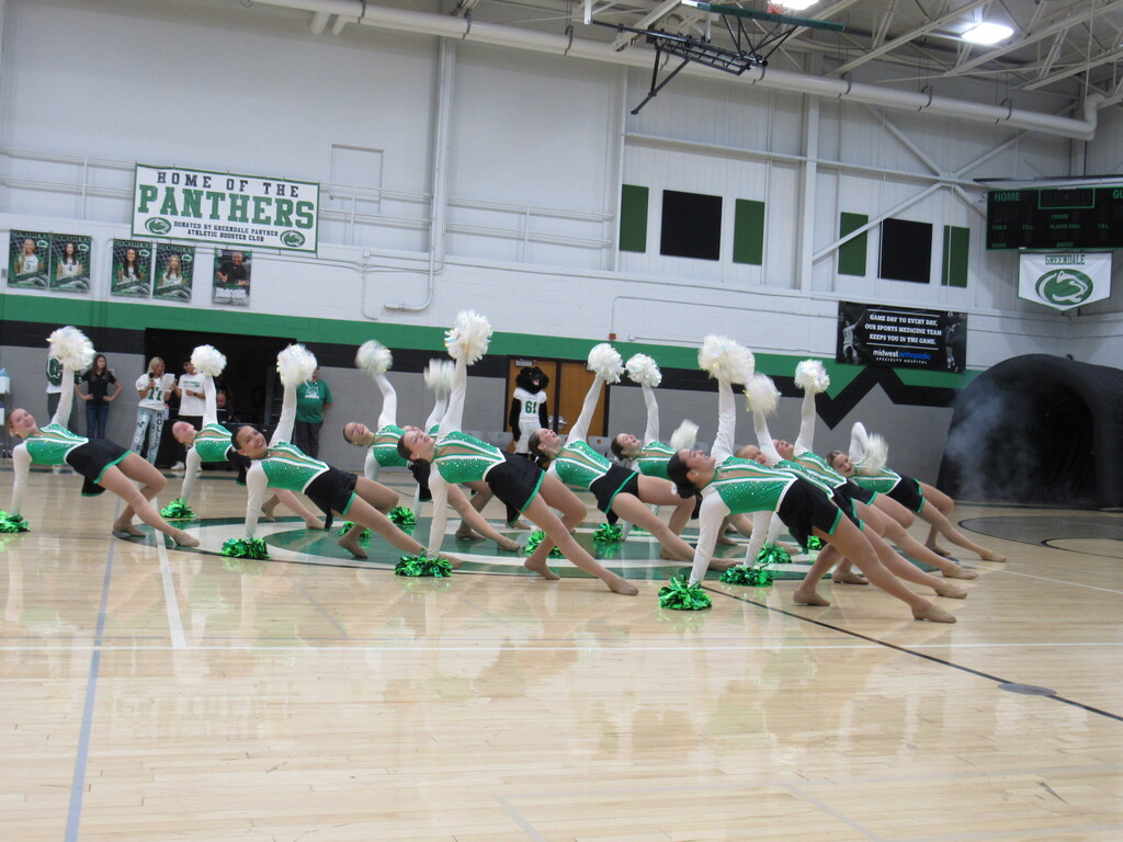 Girls in poms costume posing on the floor during a routine