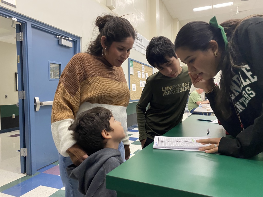 A family of three checking in with a staff member at the entrance.