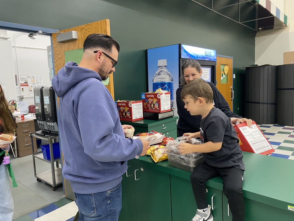 A little boy sitting on a counter and giving a man something for his meal
