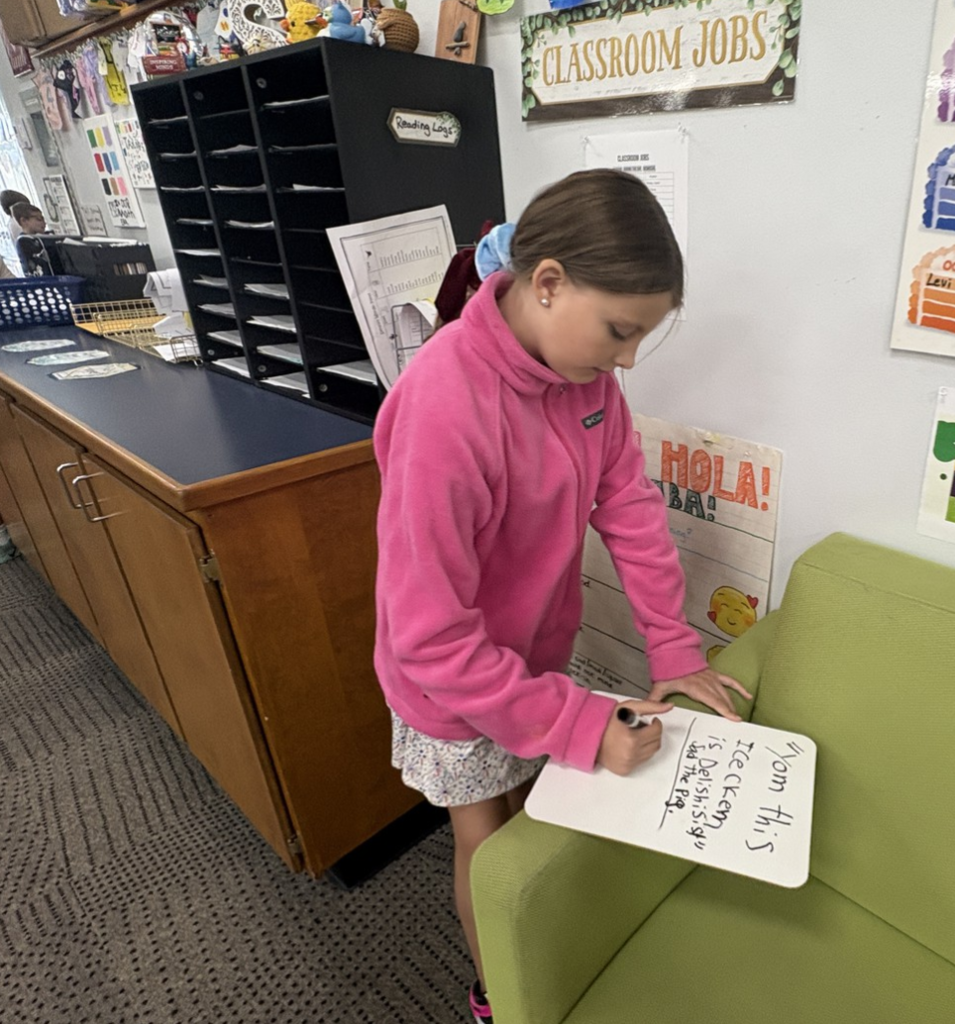 Fourth grader writing on a small hand-held white board.