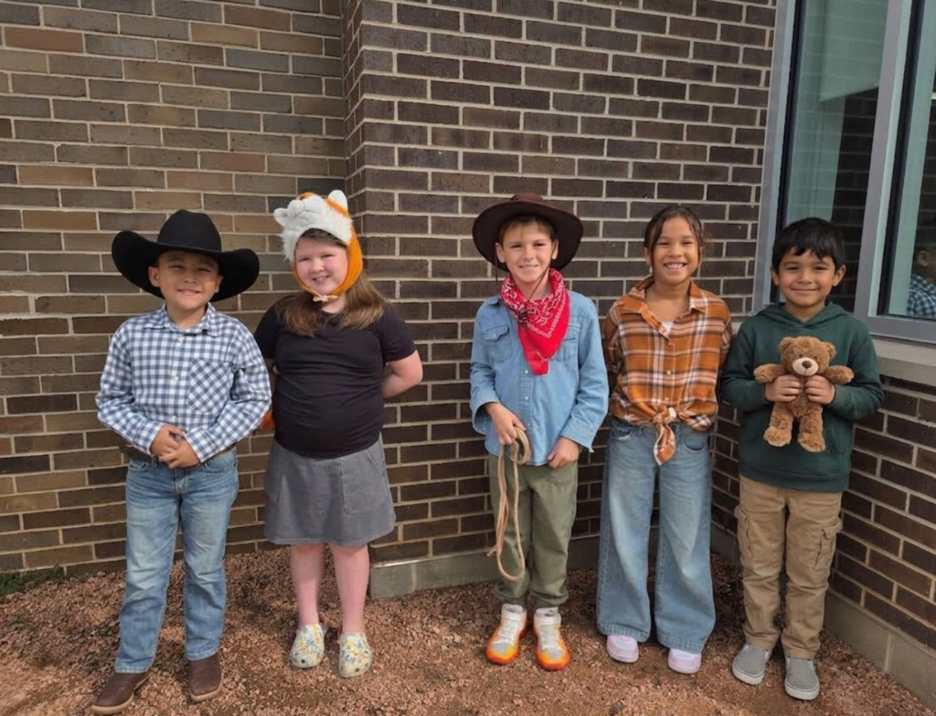 Five smiling second graders dressed as favorite characters from fairy tales and tall tales.