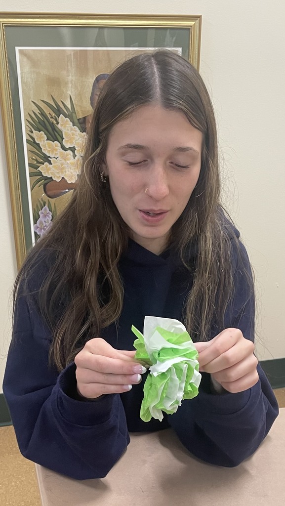 Student holds a paper flower to show off her work.