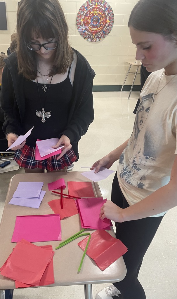 Two students stand and select materials to make paper flowers.
