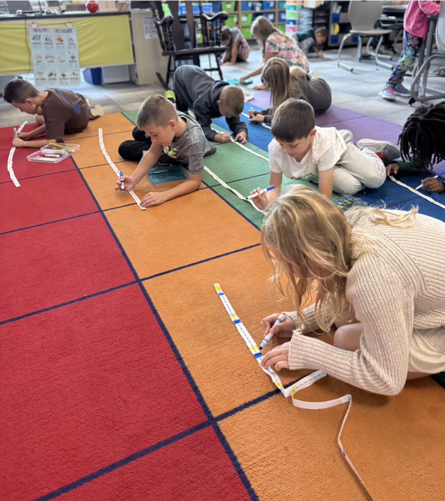 A bunch of third graders work on the floor with number lines.