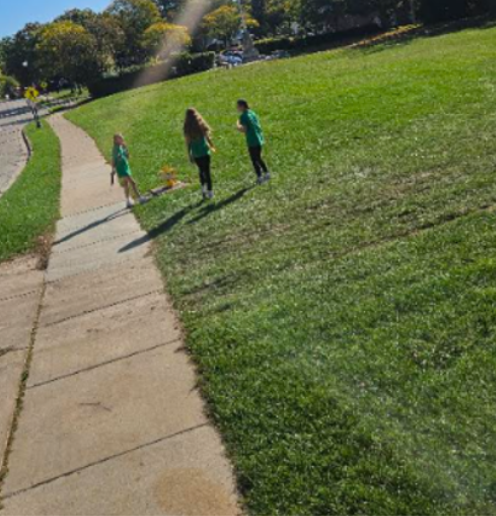 Three students standing in a grassy field getting ready to throw their disks in a round of disk golf.