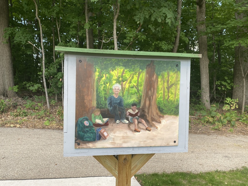 Portrait of a women reading in a woods with two students.