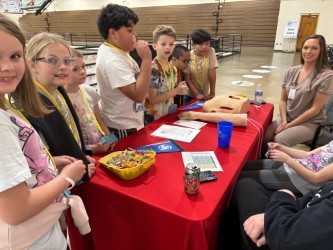 young students stand in front of a red table with prosethetics'