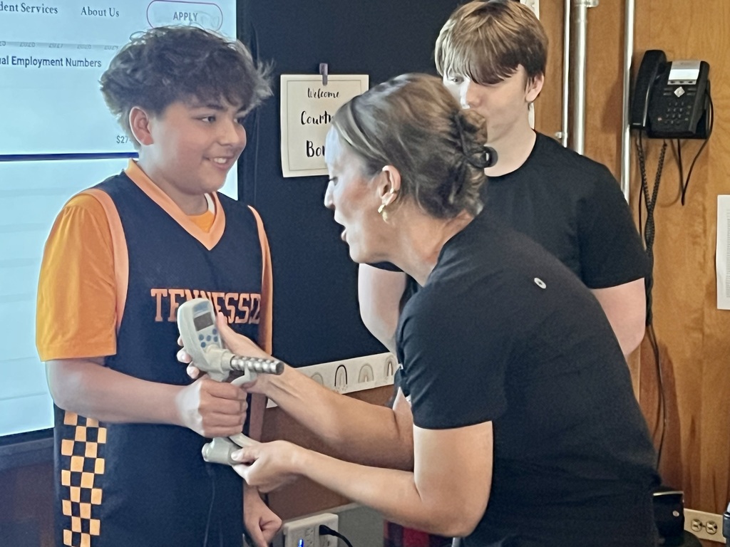 Adult demonstrating equipment to a student during a classroom career activity.