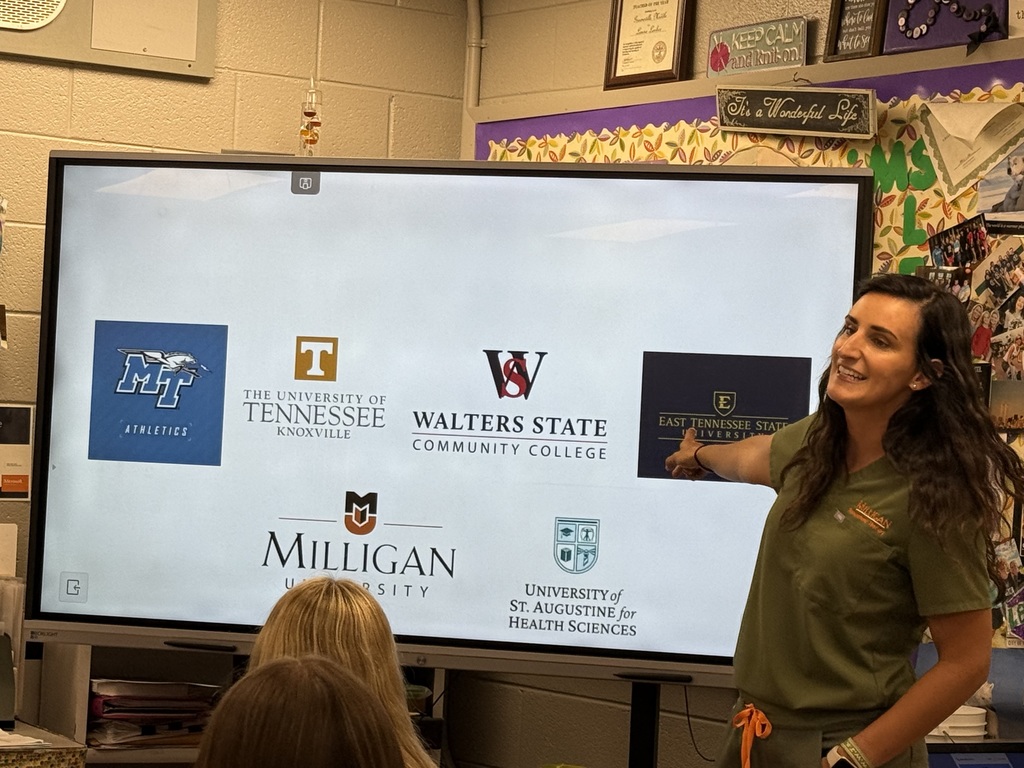 Presenter pointing to college and university logos during a classroom presentation.