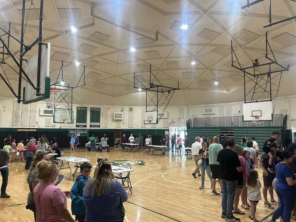 a large crowd of parents and students walk around a school gymnasium