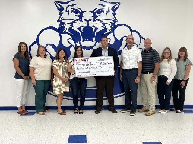 Chris Kell holding a $10,000 check