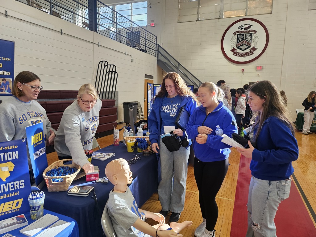 Photo of three high school students speaking with two presenters at their table