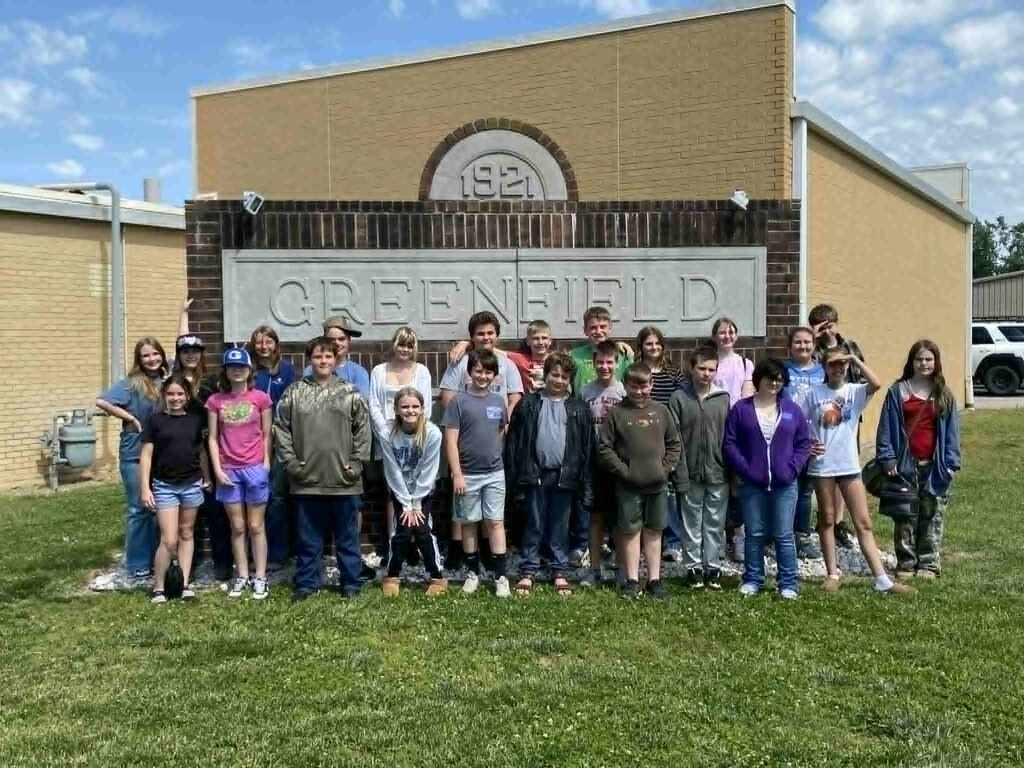 image of 6th grade students outside in front of a large sign that reads 1921 GREENFIELD