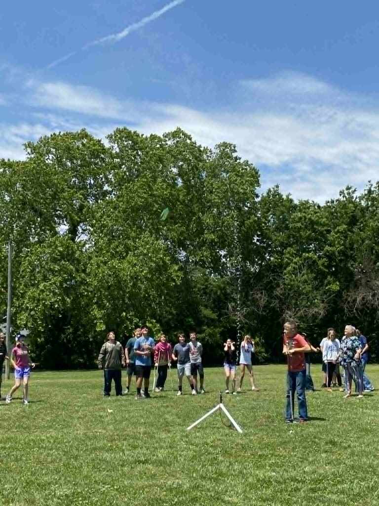 image of students watching a water rocket science demonstration outside