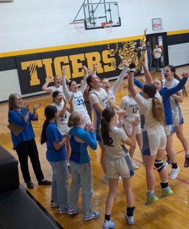 Image of high school girls basketball team and coach celebrating a win on the court