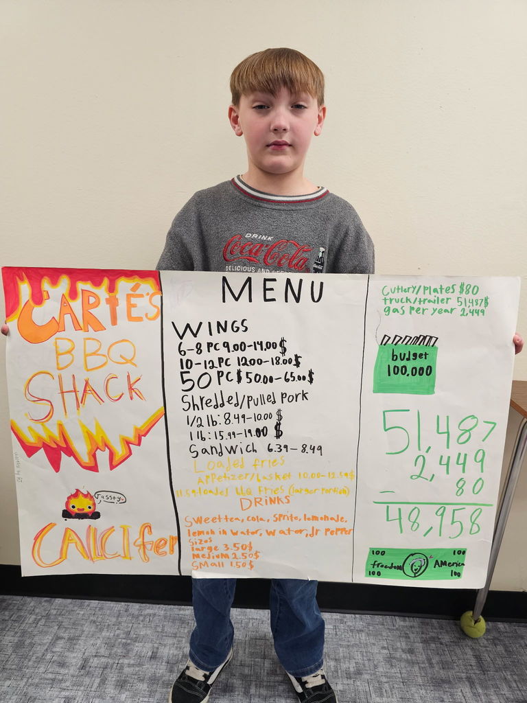 student holding up a menu he created cartes bbq shack with menu items