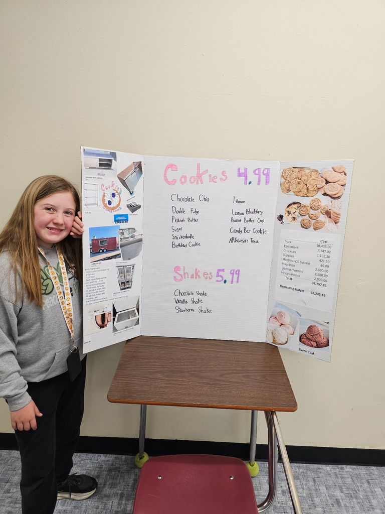 student standing by menu of a cookie shop she created
