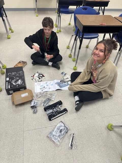 two students building a robotic arm