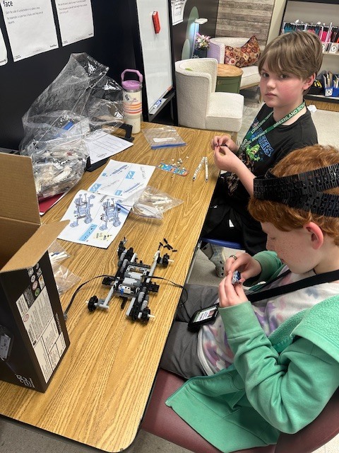 two students building a robotic arm