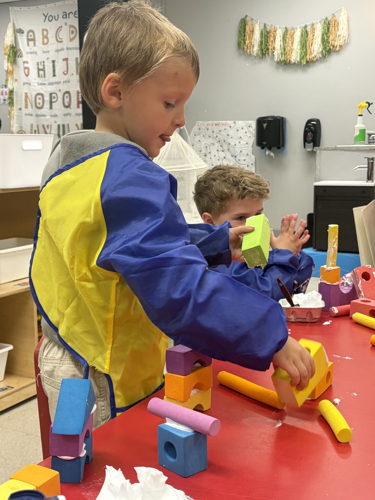 two preschool students building a treehouse with blocks
