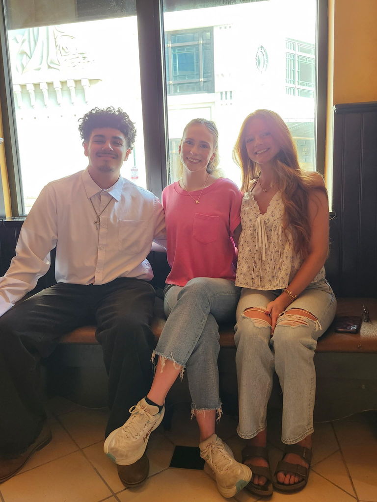 three students posing in front of a window