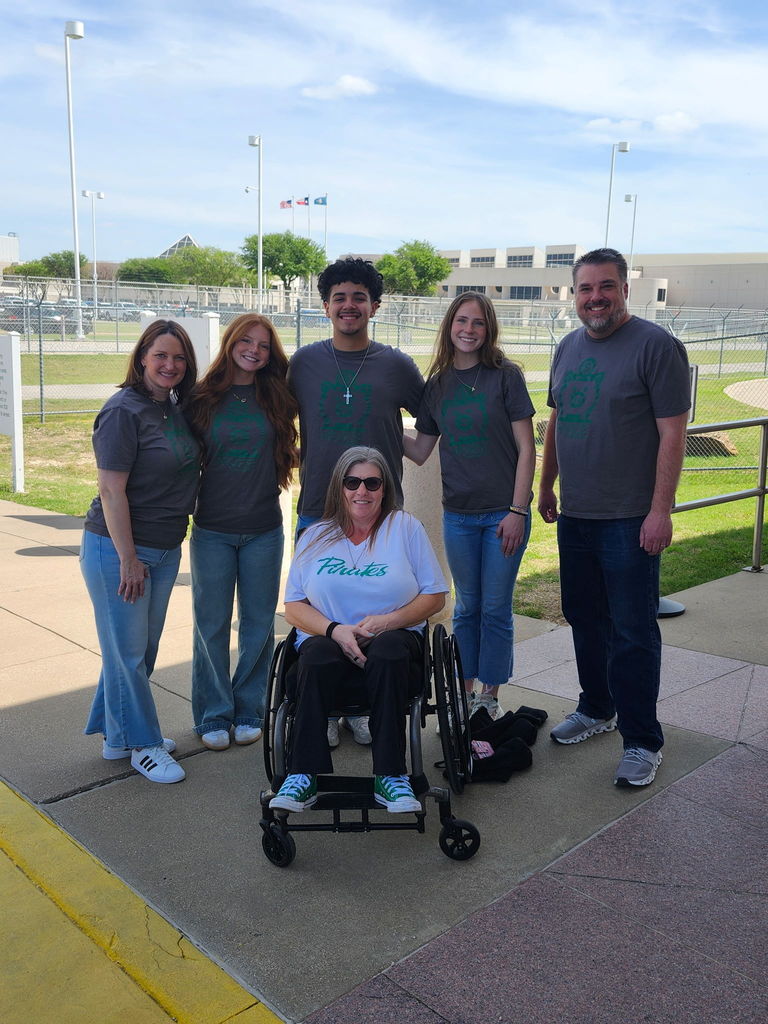students posing in front of a fenced in area