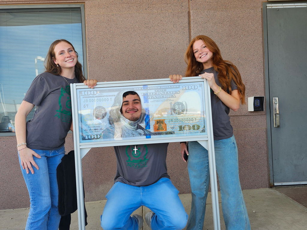 students posing with a $100 bill