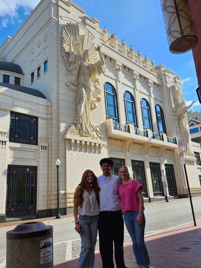 three students standing in front of an unnamed building