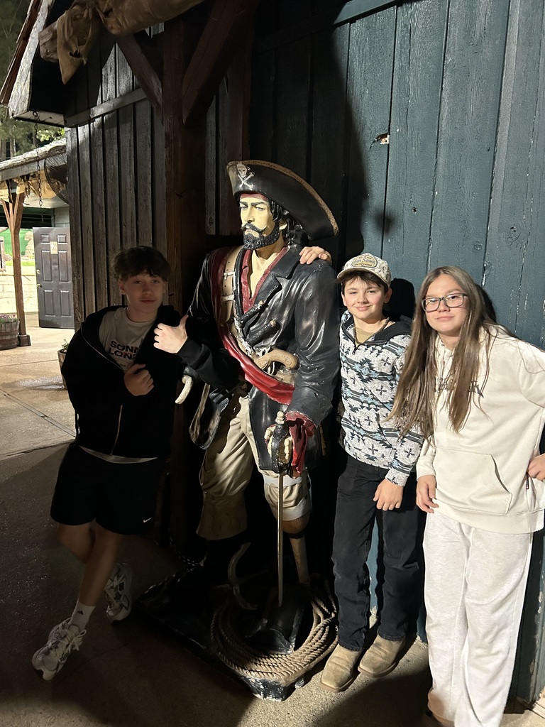students posing beside a pirate statue