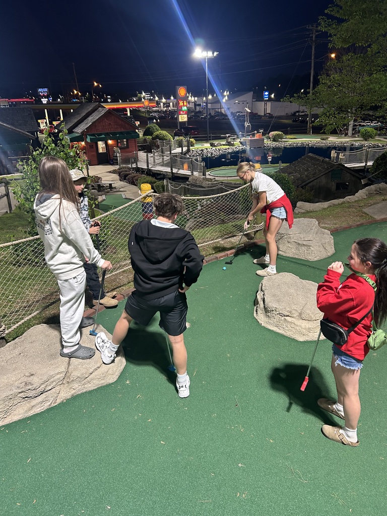 four students playing mini golf