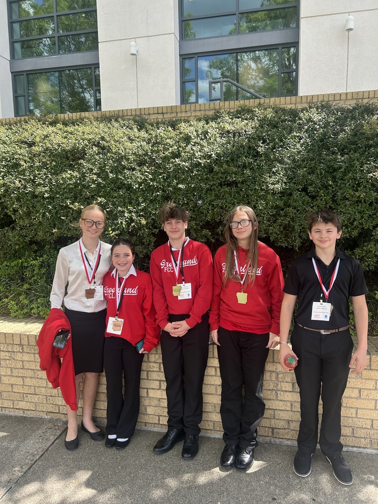 four students posing outside in front of greenery