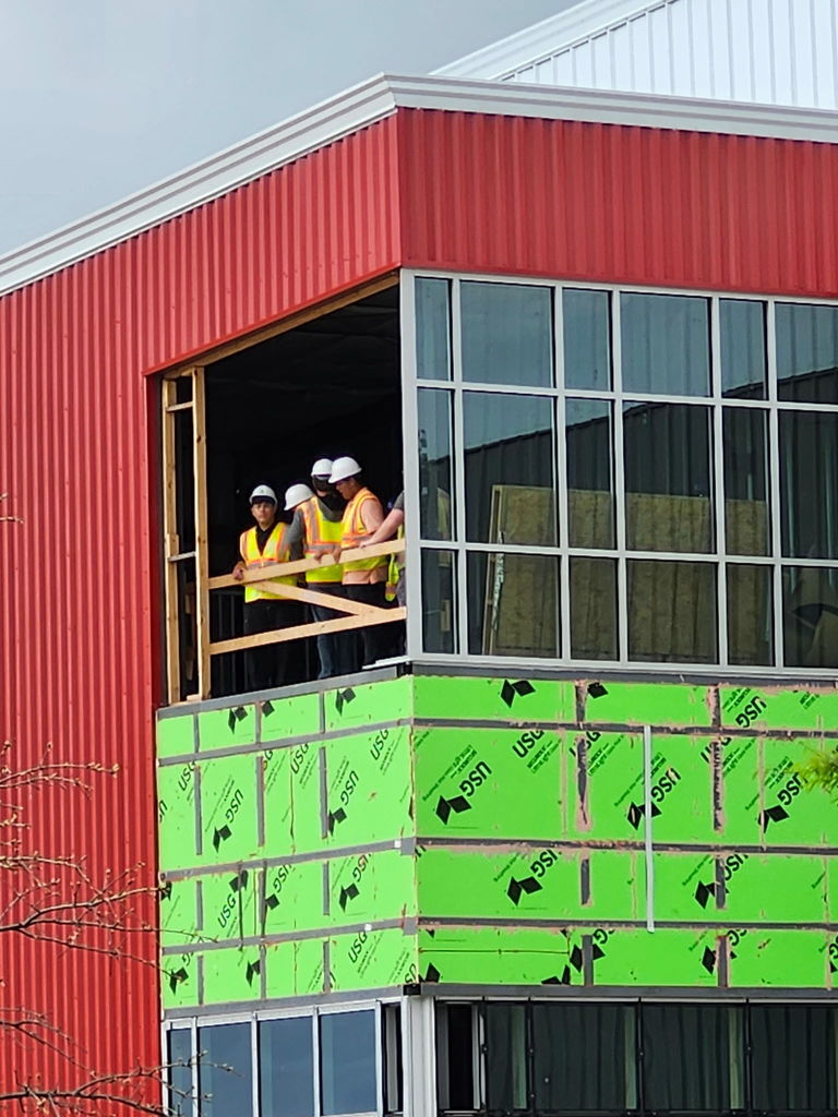 students standing at the window of a building being constructed