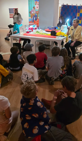 students sitting on the floor listening to a speaker