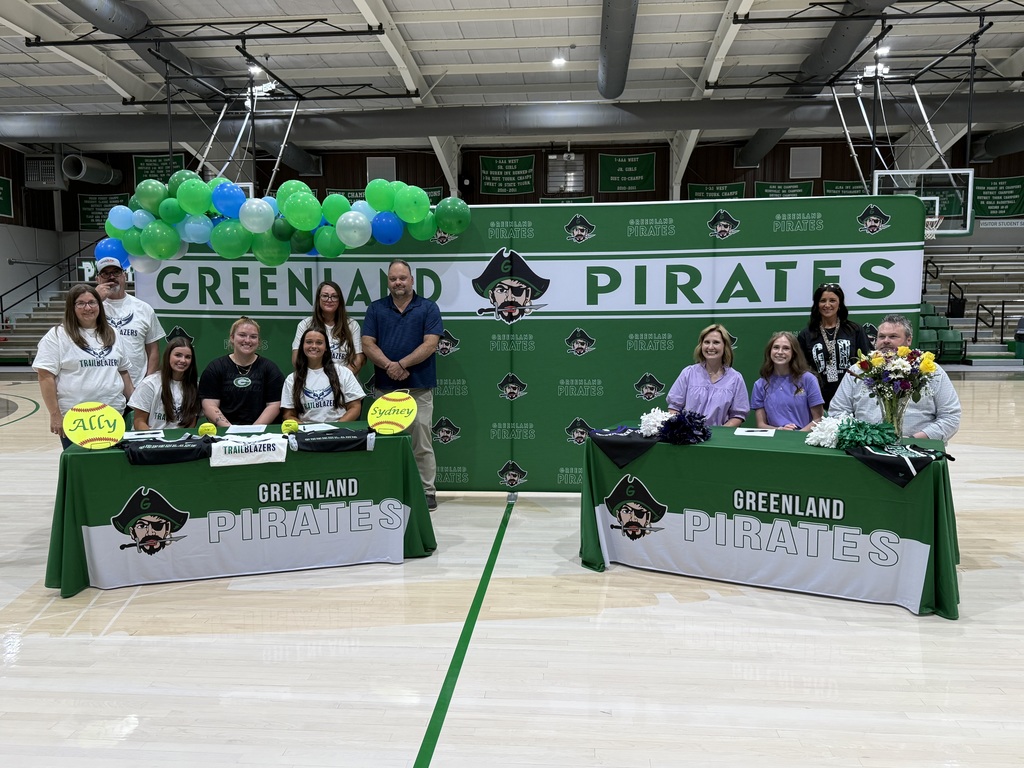three families sitting at tables in front of a greenland pirate banner with sports equipment on tables