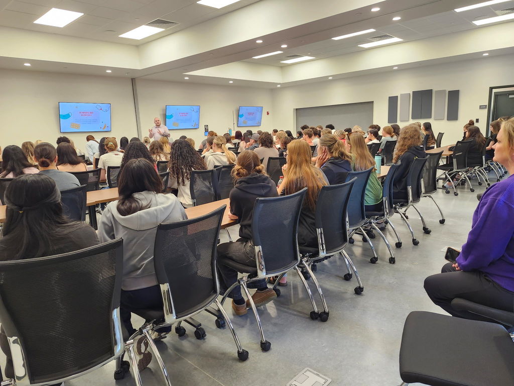 students sitting at tables listening to a speaker