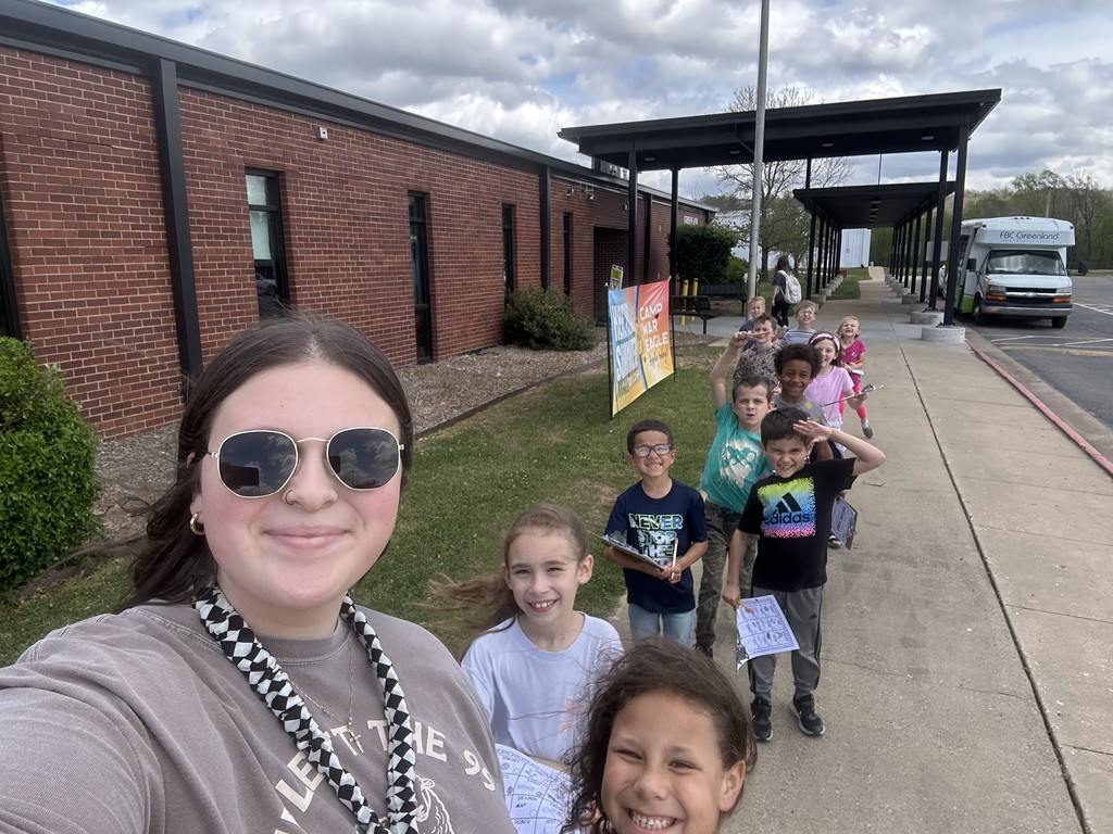 students and teacher walking in front of school