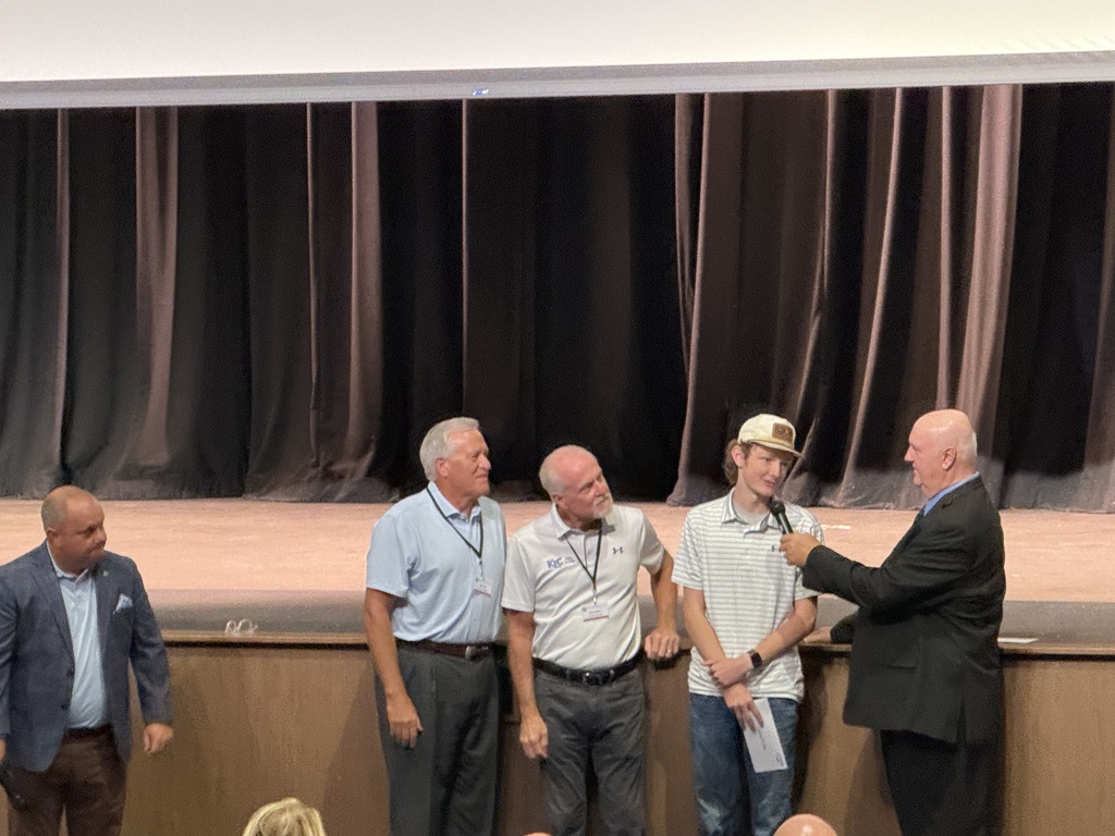 4 people standing together with one talking in a microphone