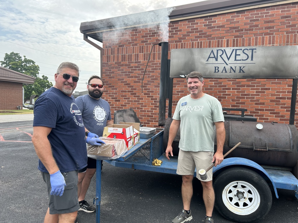 Three people standing at a grill