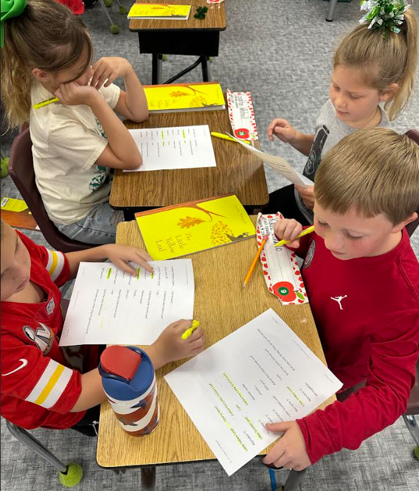 4 students sitting at desks reading